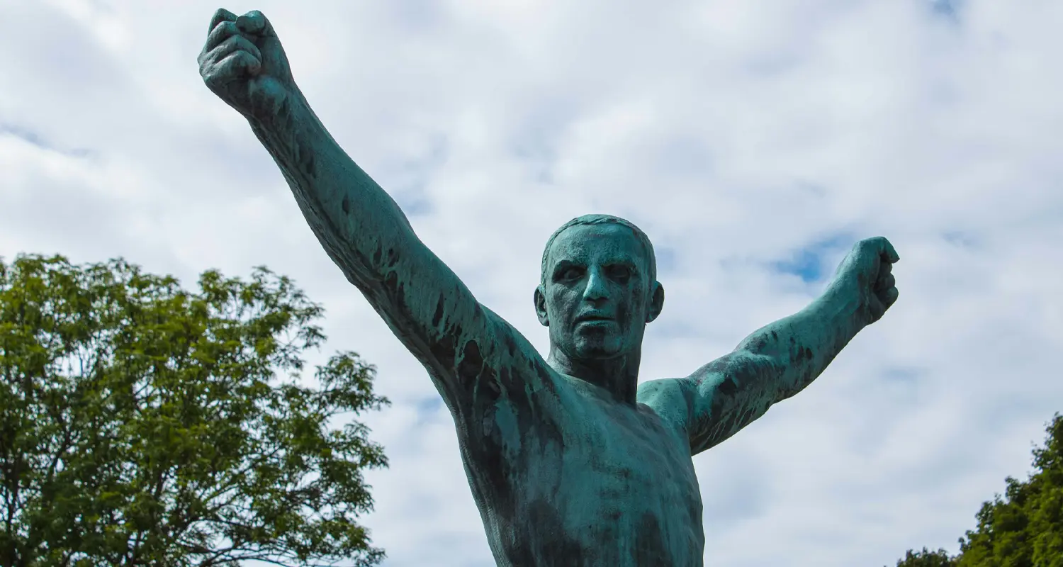 Bronze sculpture of a man with raised fists in Vigeland Park, Oslo Caption: Vigeland's figures are rarely calm. That's the point.