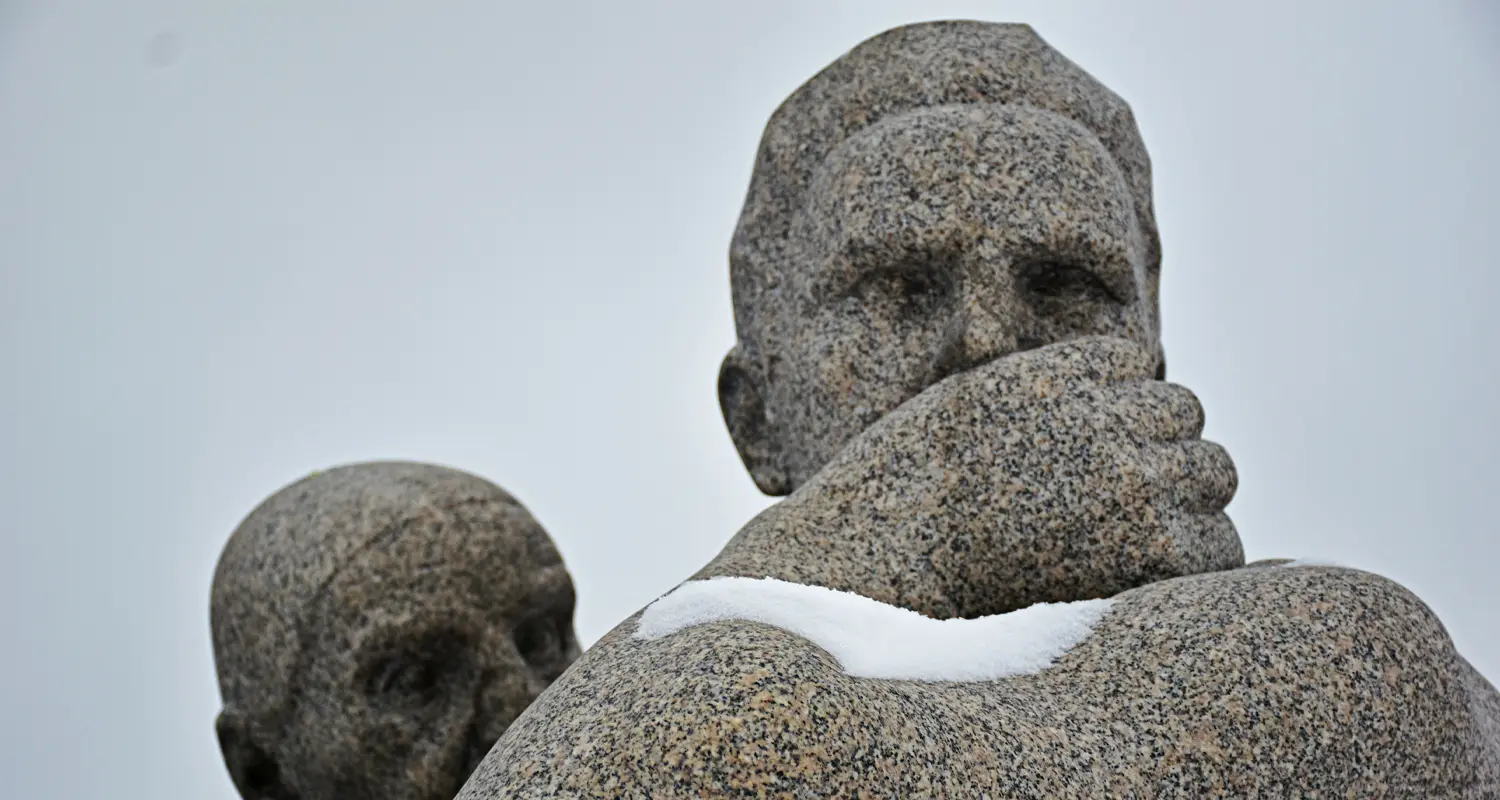 Granite sculptures in Vigeland Park covered in snow in winter Caption: Winter thins the crowds and changes the sculptures completely.